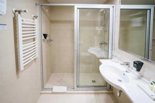 a bathroom with a glass shower and a sink at Hotel Monogram Park in Ruma