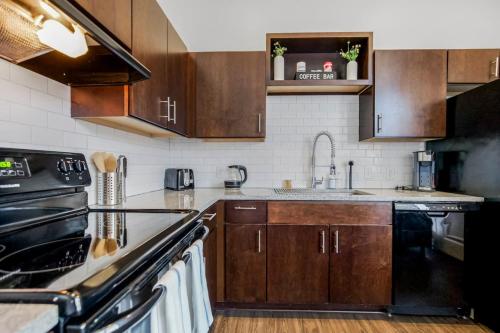 a kitchen with wooden cabinets and a stove top oven at Classy 2BR-Parking, Rooftop,Near Arrowhd & TMobile in Kansas City