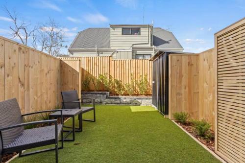 a backyard with a wooden fence and grass at Auckland Peninsula Stunner in Auckland