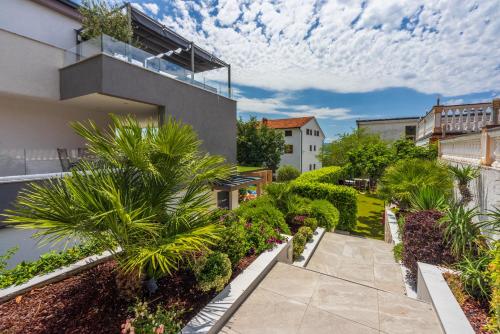 a garden with palm trees and a walkway at Relax Derossi 2 in Crikvenica