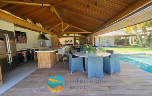 a patio with a table and a kitchen and a pool at Villa Biarritz, Praia do Forte in Praia do Forte