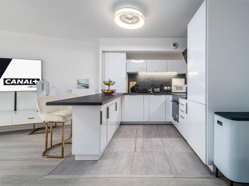 une cuisine avec des armoires blanches et un comptoir noir dans l'établissement Chambre raffinée - Chelles, à Chelles