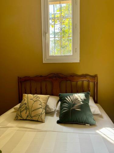 a bed with two pillows on it with a window at Charmante maison provençale in Les Taillades