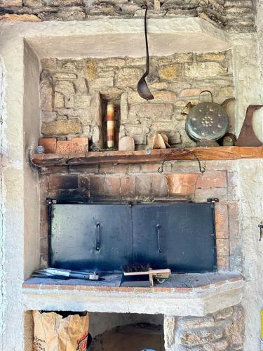 a stone fireplace with a stove in a room at Charmante maison provençale in Les Taillades