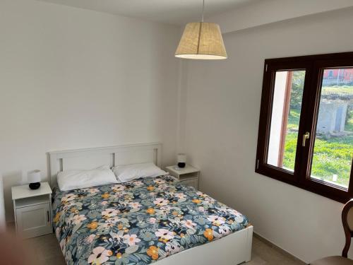 a bedroom with a bed with a floral comforter and a window at Villa Santa Lucia in Noto