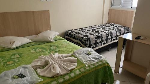 a room with two beds and a table and a bed at Pousada Soares in Aparecida