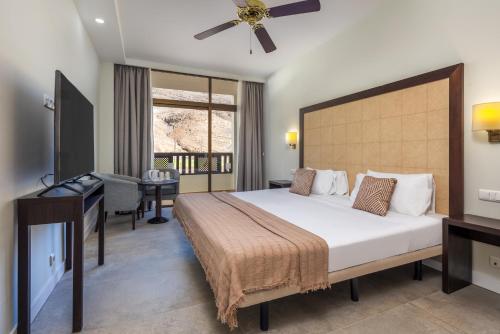 莫罗德哈布雷Hotel LIVVO Jandía Golf的一间带大床和书桌的卧室