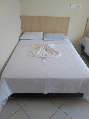 a large bed with a white bedspread on it at Pousada Soares in Aparecida