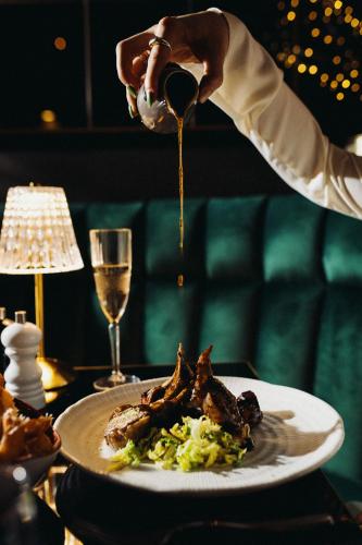 a person pouring sauce onto a plate of food at The Chesterton Hotel in Bicester