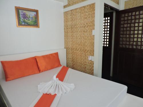 a bedroom with a white bed with an orange pillow at Orange Mangrove Pension House by SMS Hospitality in Puerto Princesa City