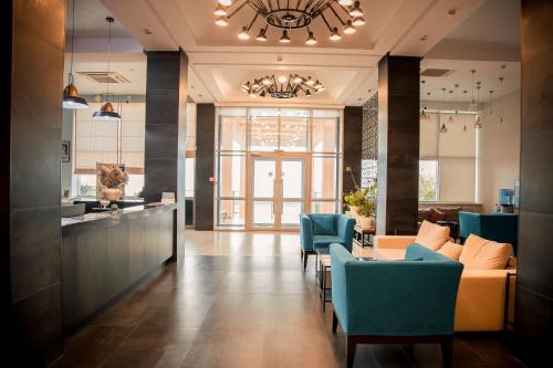 a living room with blue chairs and a kitchen at MIRAMAR Apart Hotel & SPA in Aktau