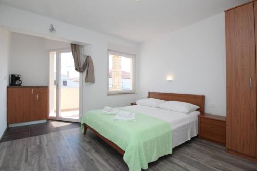 a bedroom with a bed with a green blanket on it at Apartments & Rooms Dekanic in Baška