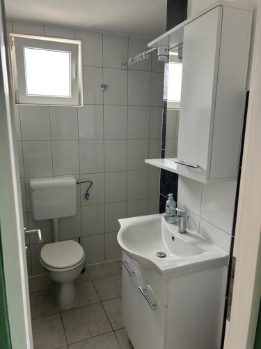 biała łazienka z toaletą i umywalką w obiekcie Apartmani Starcevic w mieście Vir