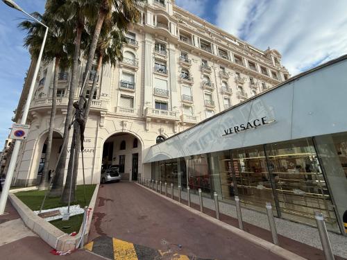 un grand bâtiment blanc avec un magasin dans une rue dans l'établissement Cannes Croisette Miramar escape, à Cannes