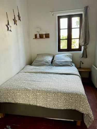 a bed in a bedroom with a window at La maison Haut-perché townhouse with view and jacuzzi in Saumane-de-Vaucluse