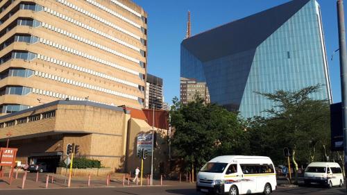 two white vans parked in front of a large building at The Franklin Luxury Condo with UPS for Wi-Fi in Johannesburg