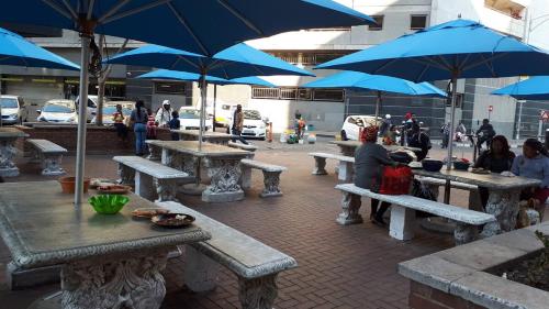 a group of picnic tables with blue umbrellas at The Franklin Luxury Condo with UPS for Wi-Fi in Johannesburg