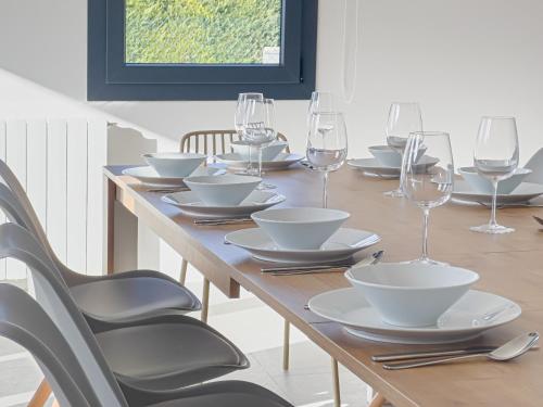 a wooden table with plates and wine glasses on it at Els Majordoms - El Mont in Beuda