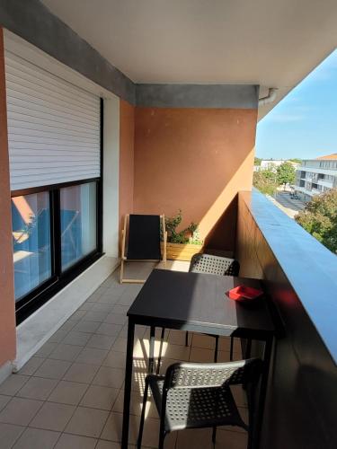 d'un balcon avec une table et des chaises noires. dans l'établissement Entre Médoc et Atlantique, 3 étoiles, calme en plein centre-ville, à Saint-Médard-en-Jalles