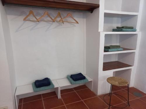 a room with white shelves and a stool and a chair at Número 55 in Órgiva