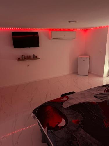 Zimmer mit einem TV und einem Bett in einem Zimmer mit roten Lichtern in der Unterkunft Love room in Camaret-sur-Aigues