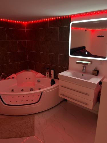 une salle de bain avec une baignoire, un lavabo et un miroir dans l'établissement Love room, à Camaret-sur-Aigues
