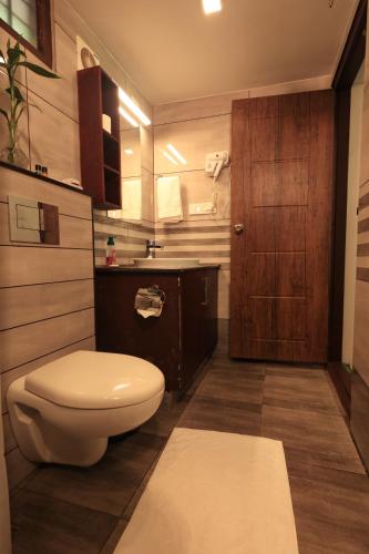 a bathroom with a white toilet and a wooden door at Bamboo Grove in Mānantoddy