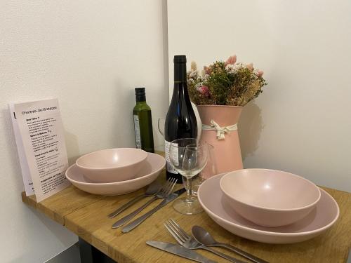 - une table avec deux assiettes et une bouteille de vin dans l'établissement LogeYou, à Chartres-de-Bretagne