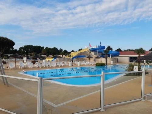 a large swimming pool with chairs and a fence at Mobil Home Moderne de 40m2 TOUT CONFORT Camping SIBLU Les CHARMETTES 785 La Palmyre Les Mathes in Les Mathes