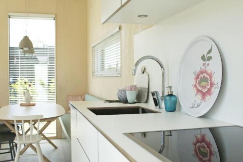 a white kitchen with a sink and a table at Zondag aan Zee - Ecohuisjes Terschelling in Midsland