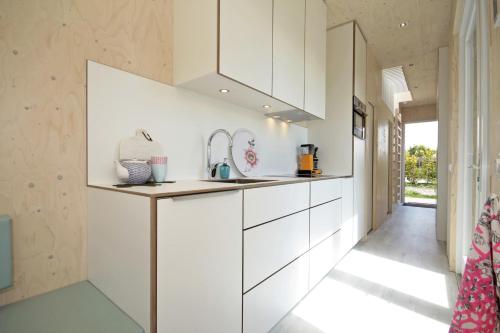 a kitchen with white cabinets and a sink at Zondag aan Zee - Ecohuisjes Terschelling in Midsland