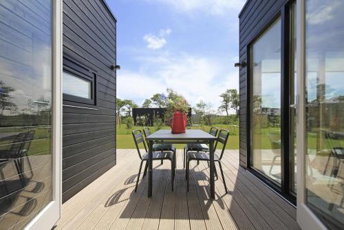 a patio with a table and chairs on a deck at Zondag aan Zee - Ecohuisjes Terschelling in Midsland