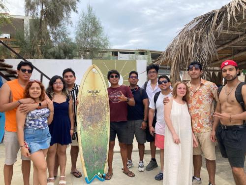 a group of people posing for a picture with a surfboard at Casa Tarantini in Lobitos