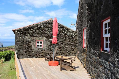 a wooden deck with a chair and an umbrella at Aldeia das Cagarras in Santo Amaro