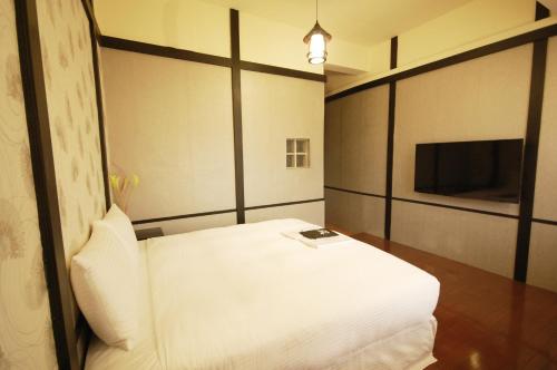 a bedroom with a white bed and a television at Hananoi Bed and Breakfast in Hengchun