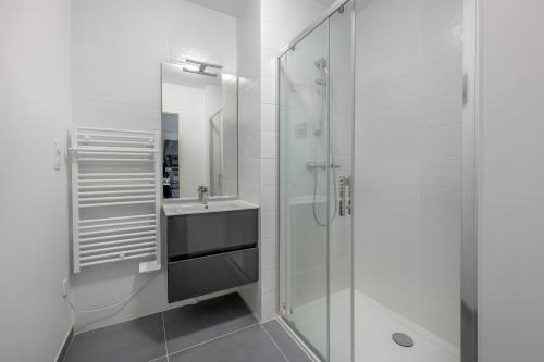 a white bathroom with a sink and a shower at Appartement pour 4 à 150m de la Mer in Sainte-Marie