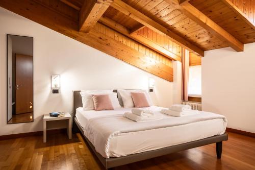 a bedroom with a large white bed with wooden ceilings at Appartamento La diMosa in Dro