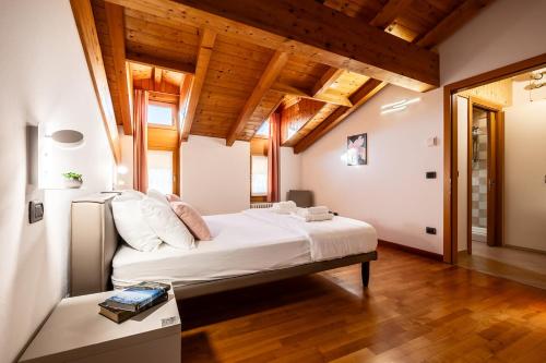 a bedroom with a large white bed with wooden ceilings at Appartamento La diMosa in Dro