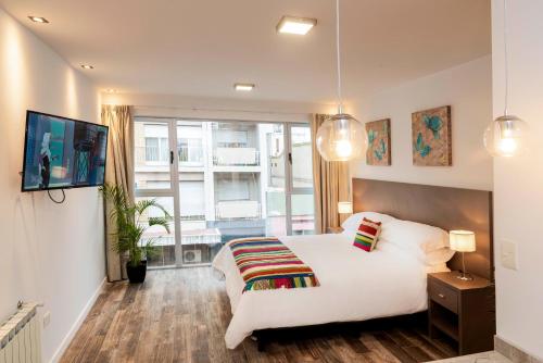 a bedroom with a white bed and a large window at Magna Suites in Bahía Blanca