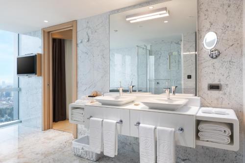 a bathroom with two sinks and a large mirror at Wyndham Grand Istanbul Levent Hotel & Conference Center in Istanbul