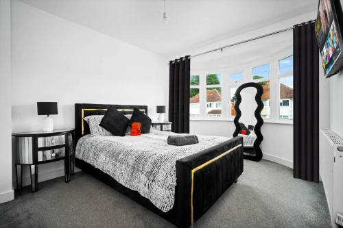 a bedroom with a black and white bed and a window at The Rock, Elegant 4 Bedroom House, Solihull, close to NEC, sleeps 8 in Birmingham
