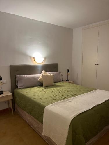 ein Schlafzimmer mit einem Bett mit einer grünen Bettdecke in der Unterkunft Tossa de Mar - TROPICANA in Tossa de Mar