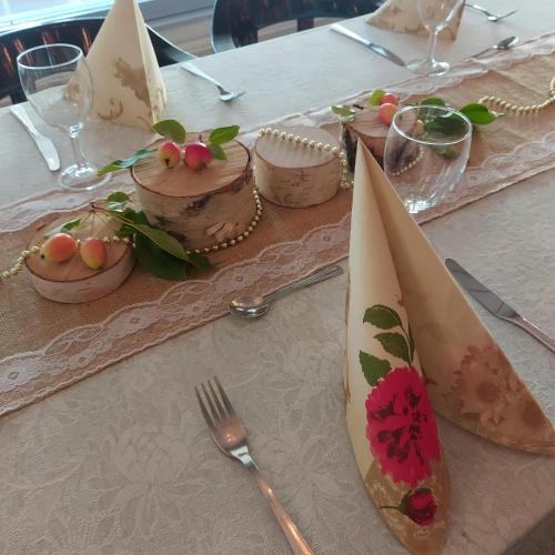 a table with a white table cloth with plates and forks at Maalaiskartano Pihkala in Kestilä
