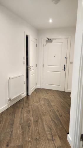 an empty room with two white doors and wooden floors at Modern 2 Bedroom Apartment in Grays Thurrock