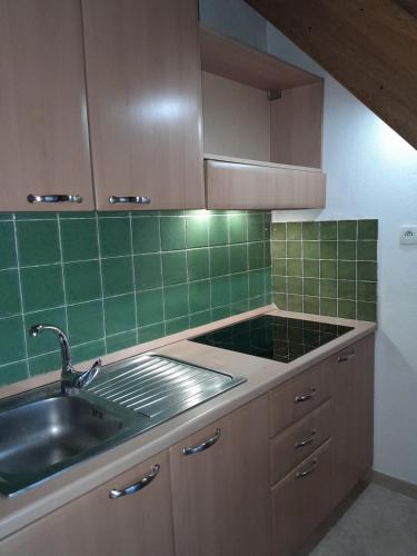Il comprend une cuisine avec un évier et un mur carrelé vert. dans l'établissement Appartement Jardin de la Mer, à Linguizzetta