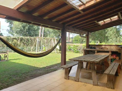 - une table de pique-nique en bois sous un pavillon avec hamac dans l'établissement Agréable maison bien située, à Capbreton