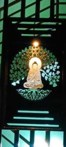 a light hanging from a ceiling with a sign on it at Budha Home Stay in Hampi
