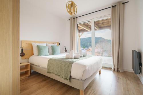 une chambre avec un lit et une grande fenêtre dans l'établissement L’Alma - Magnifique maison avec jacuzzi, à Gérardmer