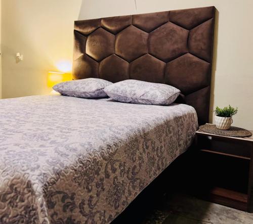 a bed with a brown headboard and two pillows at Casa Josefina Allende Nuevo Leon in Allende