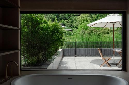 La salle de bains est pourvue d'une baignoire et d'une terrasse avec un parasol. dans l'établissement Anji ke gamer wild luxury Resort villa, à Anji
